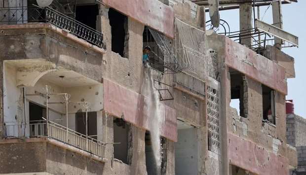 A man throws out debris from an apartment building in Douma, outside Damascus, Syria