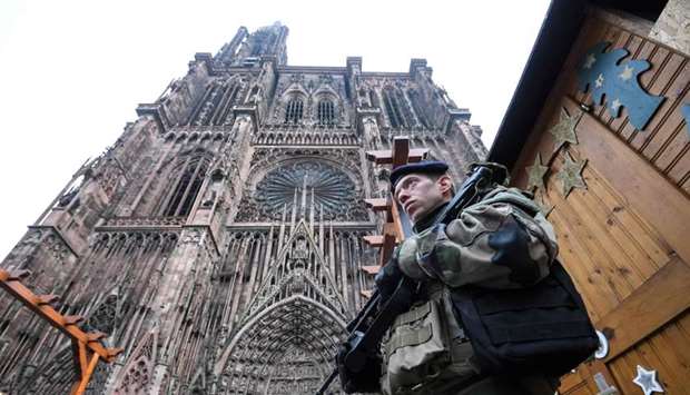 French soldiers stand guard at the Christmas market in front of the Cathedral as policemen conduct a search in order to find the gunman who opened fire near a Christmas market the night before, in Strasbourg, eastern France.