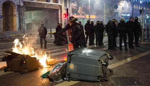 Riot police extinguish a fire during a demonstration by Yellow Vests (Gilets jaunes) against rising oil prices and living costs in Marseille