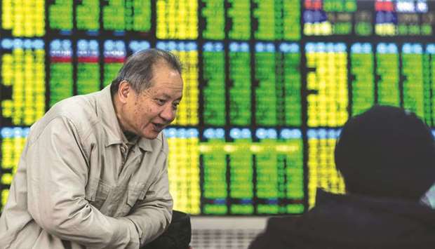 Two investors chat while keeping an eye on stock price movements shown on a screen at a securities company in Shanghai.  Shanghai stocks surged 1.2% to 2,634.09 yesterday on hopes China will unveil monetary easing measures to coincide with the 40th anniversary of its economic awakening next week.