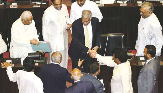 Members of parliament shake hands with ousted prime minister Ranil Wickremesinghe, centre, during a parliament session in Colombo yesterday.