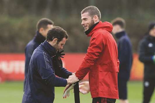 Manchester United midfielder Juan Mata (left) wraps the gloves for teammate and goalkeeper David de Gea during a training session at the Carrington Training complex in Manchester, England, on Tuesday. (AFP)