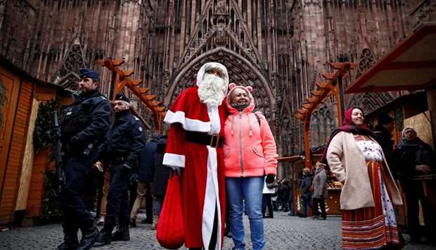 French police patrol outside the Strasbourg Cathedral as a man dressed as Father Christmas poses with a tourist, in Strasbourg, France