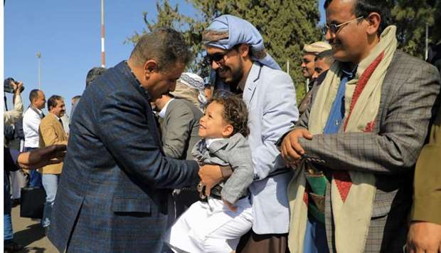 A member of the Houthi delegation (L) returning from peace talks in Sweden greets a supporter and child upon arrival at Sanaa International Airport in the Yemeni capital
