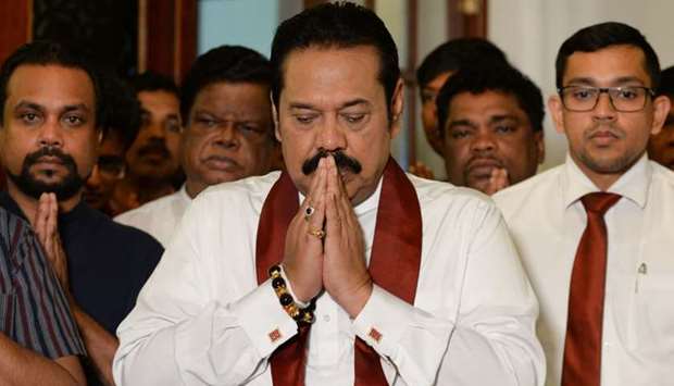 Sri Lankau2019s former president Mahinda Rajapakse gestures during a ceremony before signing a document backing down from his controversial appointment as prime minister in Colombo