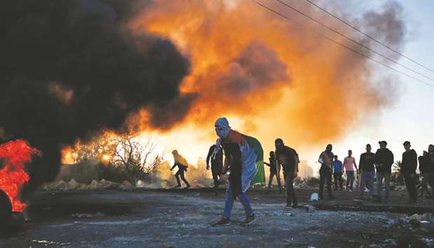 Palestinian protesters stand amid smoke during clashes with Israeli troops in Ramallah, in the occupied West Bank, yesterday.