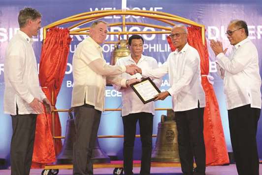 President Rodrigo Duterte watches as Defence Secretary Delfin Lorenzana (second right) receives a certificate of transfer for three Balangiga church bells from the US embassy in Manilau2019s deputy chief of mission, John Law (second left), during a ceremony in Balangiga in Eastern Samar province yesterday, as US Deputy Assistant Secretary of Defence for South and Southeast Asia Joseph Felter (left) and Philippine Foreign Affairs spokesman Ernesto Abella (right) look on.