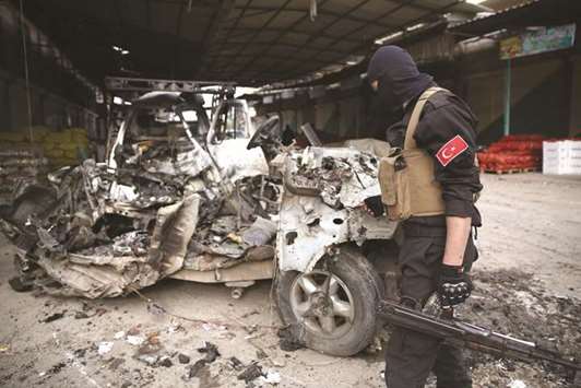 A pro-Turkish Syrian fighter inspects the remains of a car that reportedly exploded in a market in the northern Syrian city of Afrin, killing and wounding several people, yesterday.