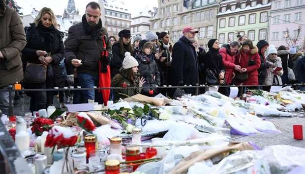 People light-up candles and deposit flowers during a gathering around a makeshift memorial at Place Kleber, in Strasbourg