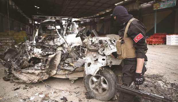 A pro-Turkish Syrian fighter inspects the remains of a car that reportedly exploded in a market in the northern Syrian city of Afrin, killing and wounding several people, yesterday.