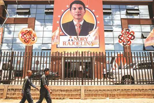 People walk by the Malagasy presidential candidate Andry Rajoelina private broadcasting building yesterday, in Antananarivo, Madagascar.