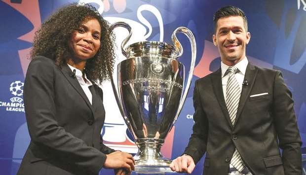 Former French player Laura Georges (L) and former Spanish player Luis Garcia pose with the UEFA Champions League trophy after the round of 16 draw at the UEFA  headquarters in Nyon yesterday.