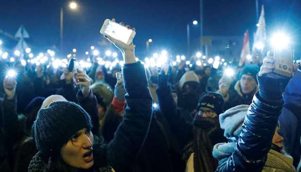 People hold up their cellphones during a protest outside the headquarters of the Hungarian state television in Budapest.