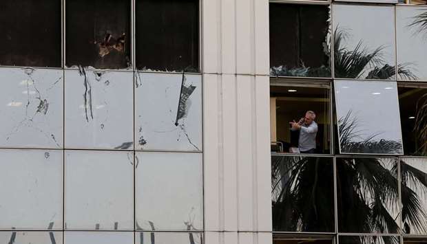 A man looks out from a broken window at the Greek Skai TV building in Athens.