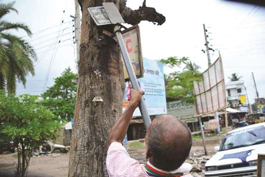 Ohid Sarder removes nails from a tree trunk near a road in Jessore, a western district of Bangladesh.