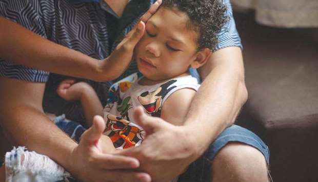 Sa Silva touches her two-year-old son Miguel, who was born with microcephaly, as her husband holds him at their apartment in Belford Roxo, Rio de Janeiro State.