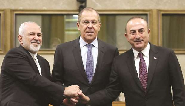 Russian Foreign Minister Sergei Lavrov, Turkish Foreign Minister Mevlut Cavusoglu and Iranian Foreign Minister Mohamed Javad Zarif shake hands as they attend a news conference after talks on forming a constitutional committee in Syria, at the United Nations in Geneva, yesterday.