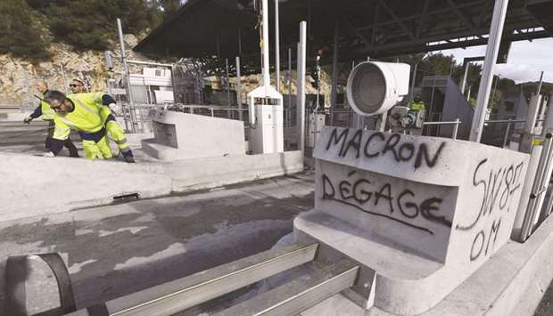 Workers of French construction group Vinci work near graffiti reading u2018Macron go awayu2019 at a highway toll station that was set on fire on Monday night in Bandol, near Marseille, southern France.