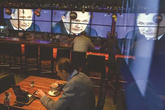 A man drinks a coffee in front of screens broadcasting Putinu2019s annual press conference, at a bar in Moscow.