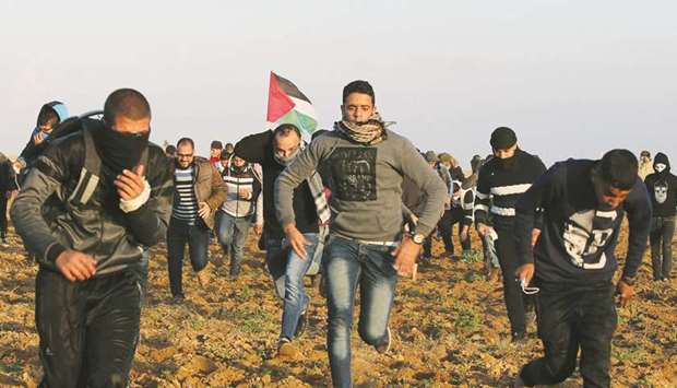 Palestinian demonstrators run for cover from Israeli gunfire and teargas during a protest near the Israel-Gaza border fence, in the southern Gaza Strip, yesterday.