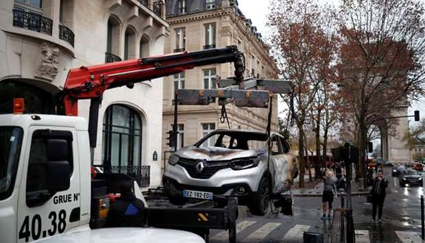 A vandalized car is removed the morning after clashes with protesters wearing yellow vests, a symbol of a French drivers' protest against higher diesel taxes, in Paris