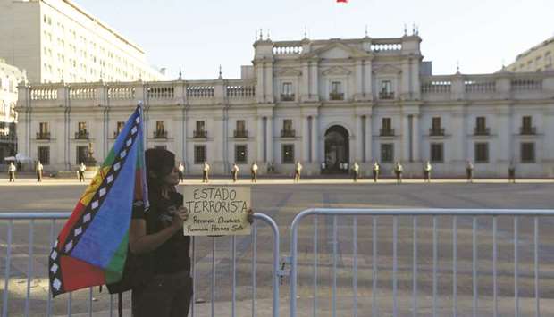 A Mapuche indigenous activist holds up a banner, which reads: u2018Terrorist Stateu2019, outside government house during a protest demanding justice for Camilo Catrillanca in Santiago.