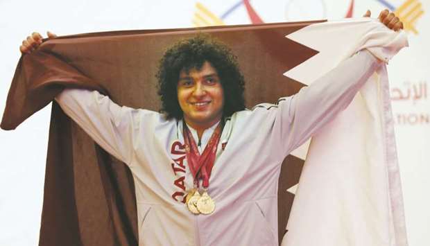 Qataru2019s Fares Ibrahim celebrates with the national flag after winning the 96kg class yesterday.