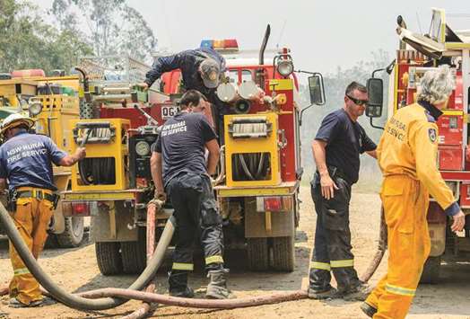 A New South Wales (NSW) Rural Fire Service crew refills their truck with water alongside Queensland firefighters as bushfires continue to burn in an area known as Captain Creek, located north of the town of Bundaberg in Queensland, Australia.