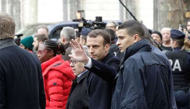 French President Emmanuel Macron (C, left) waves as he leaves the Cafe Belloy, near the Arc de Triomphe in Paris