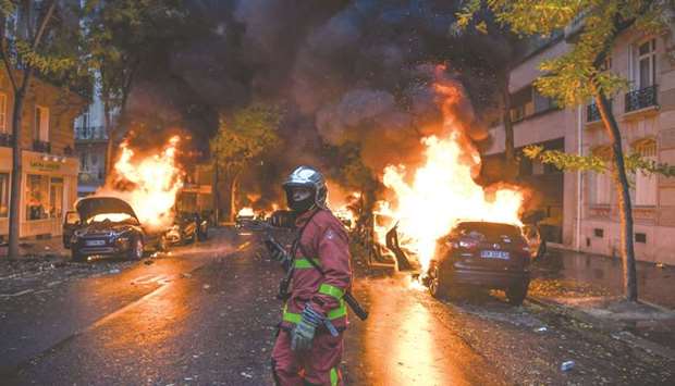 A firefighter is seen with burning vehicles in the background during a u2018yellow vestu2019 (Gilets jaunes) protest in Paris yesterday against rising oil prices and living costs.