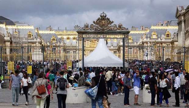 Tourists stand in queue at the entrance to the Chateau de Versailles (Versailles palace) in Versailles, near Paris