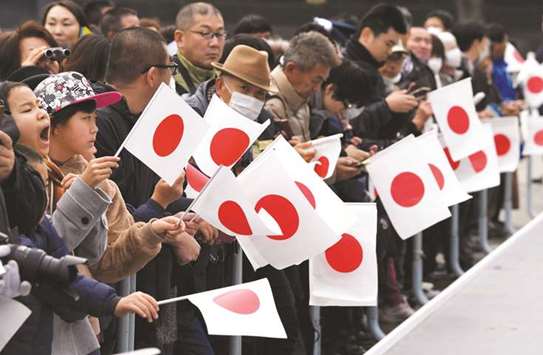 Well-wishers holding Japan flags wait for Japanu2019s Emperor Akihitou2019s birthday public appearance at Imperial Palace in Tokyo yesterday.
