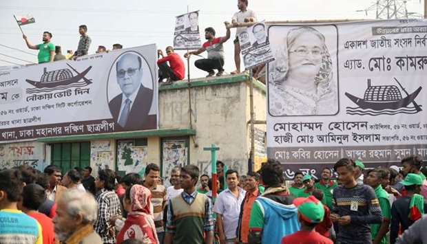 People stand on a rooftop as they join in a campaign of the Bangladesh Awami League, ahead of the 11th general election in Dhaka, Bangladesh