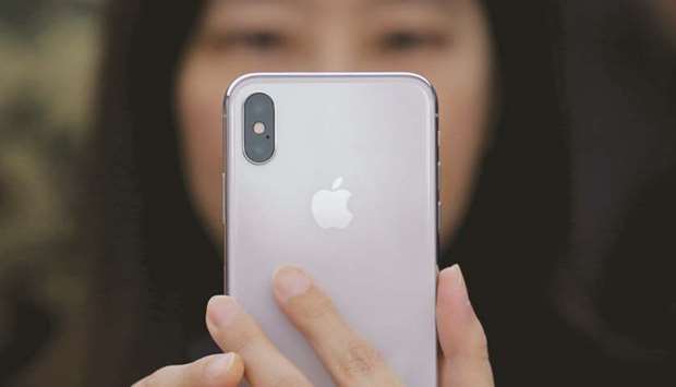 A woman uses a new iPhone X in Beijing. Extending support to Huawei which is facing immense pressure from the US, Chinese companies have rallied behind the tech giant, offering hefty discounts to employees to buy Huawei devices and shun iPhones.