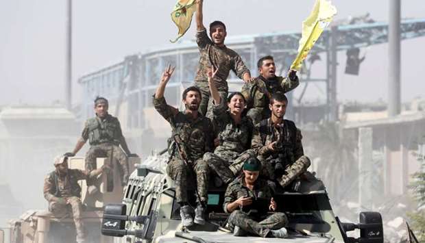 Kurdish-led militiamen ride atop military vehicles as they celebrate victory over Islamic State in Raqqa, Syria, October 17, 2017