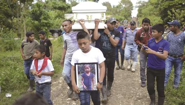 A boy carries a picture of Guatemalan seven-year-old Jakelin Caal, who died in a Texas hospital two days after being taken into custody by US border patrol agents, as her coffin is taken to the cemetery in San Antonio Secortez,  320 km north of Guatemala City, on Tuesday. Jakelin Caal died after being arrested with her father and others crossing from Mexico into the US on December 6.
