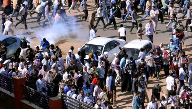 Sudanese demonstrators run from teargas lobbed to disperse them as they march along the street during anti-government protests in Khartoum, Sudan December 25