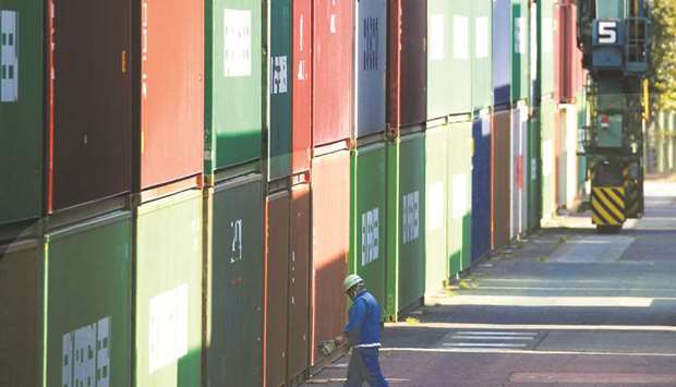 A worker walks between shipping containers at a port in Tokyo. Japanu2019s industrial output contracted in November and partially reversed the previous monthu2019s gain, while retail sales slowed sharply as increasing global risks drag on demand and threaten the countryu2019s export-reliant economy.