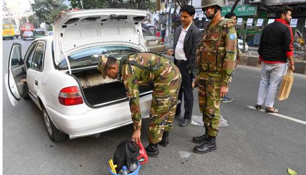 Bangladeshi army soldiers inspect a car at a roadblock ahead of December 30 general election, in Dhaka