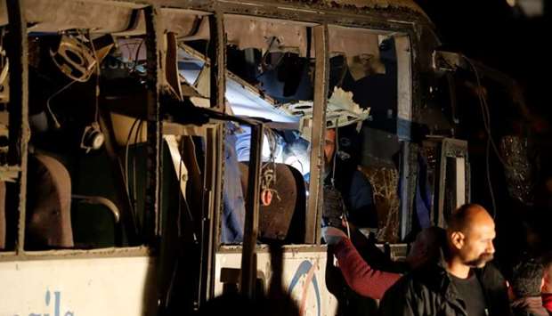 Police officers and officials inspect a scene of a bus blast  yesterday in Giza, Egypt.