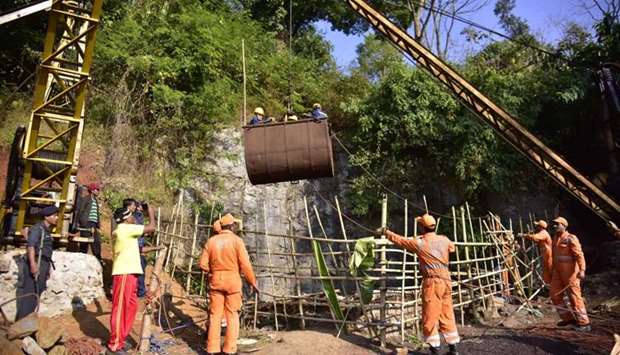 National Disaster Response Force (NDRF) personnel gather around a crane while Indian Navy divers are lifted with a pulley during rescue operations yesterday after 15 miners were trapped by flooding in an illegal coal mine in Ksan village in Meghalaya's East Jaintia Hills