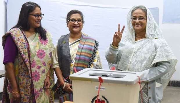 Bangladeshi Prime Minister Sheikh Hasina (R) flashes the victory symbol after casting her vote, as her daughter Saima Wazed Hossain (1st L) and her sister Sheikh Rehana (2nd L) look on at a polling station in Dhaka