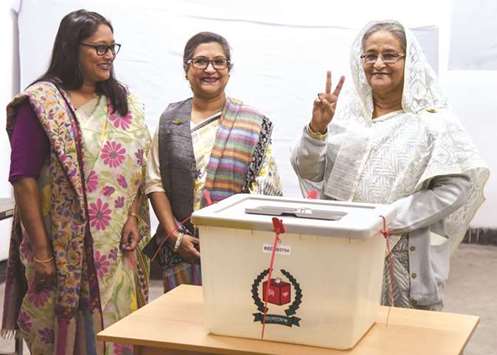 Bangladesh Prime Minister Sheikh Hasina, right, flashes the victory symbol after casting her vote, as her daughter Saima Wazed Hossain, left, and her sister Sheikh Rehana look on at a polling station in Dhaka yesterday.