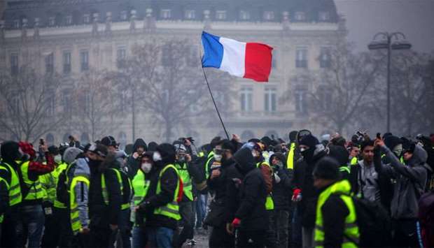 Demonstrators gather near the Arc de Triomphe as a French flag floats during a protest of Yellow vests (Gilets jaunes) against rising oil prices and living costs