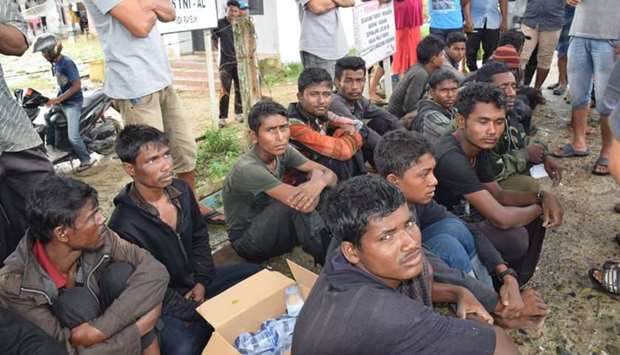 Suspected Rohingya people sit on the ground as they arrive in Idi Rayeuk, East Aceh