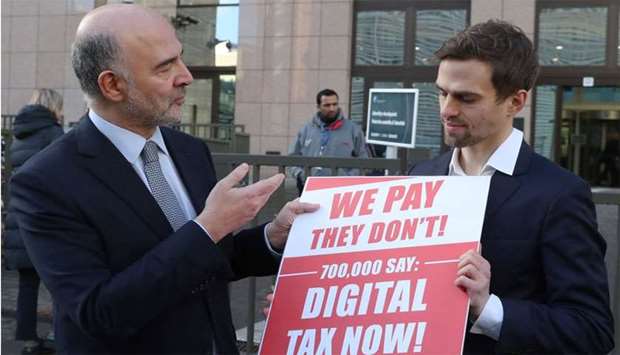 European Commissioner for Economic and Financial Affairs Pierre Moscovici receives the petition regarding the digital tax from the representative of the global activism group Avaaz, outside the EU headquarters in Brussels
