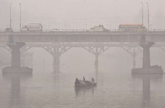 Kashmiri boatmen extract sand from the Jhelum river on a cold and foggy day in Srinagar yesterday.