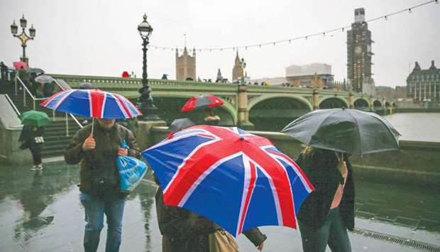 Pedestrians shelter from rain beneath Union flag-themed umbrellas as they walk along the south bank of the River Thames, near the Houses of Parliament in central London, yesterday. British MPs will hold a crucial vote on December 11 to approve or reject the Brexit deal agreed by Prime Minister Theresa May and EU leaders.
