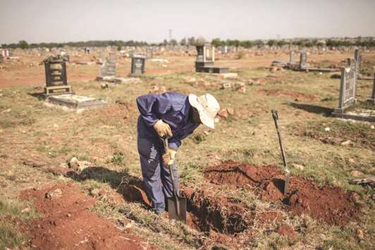 File photo shows an Avalon Cemetery worker dig a grave on the graveyard section in Soweto in Johannesburg, South Africa.