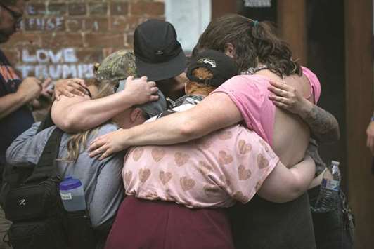 In this file photo taken on August 12, mourners embrace before the make-shift memorial to Heather Heyer in Charlottesville, on the one year anniversary of her death at the hands of a white supremacist in a speeding car.